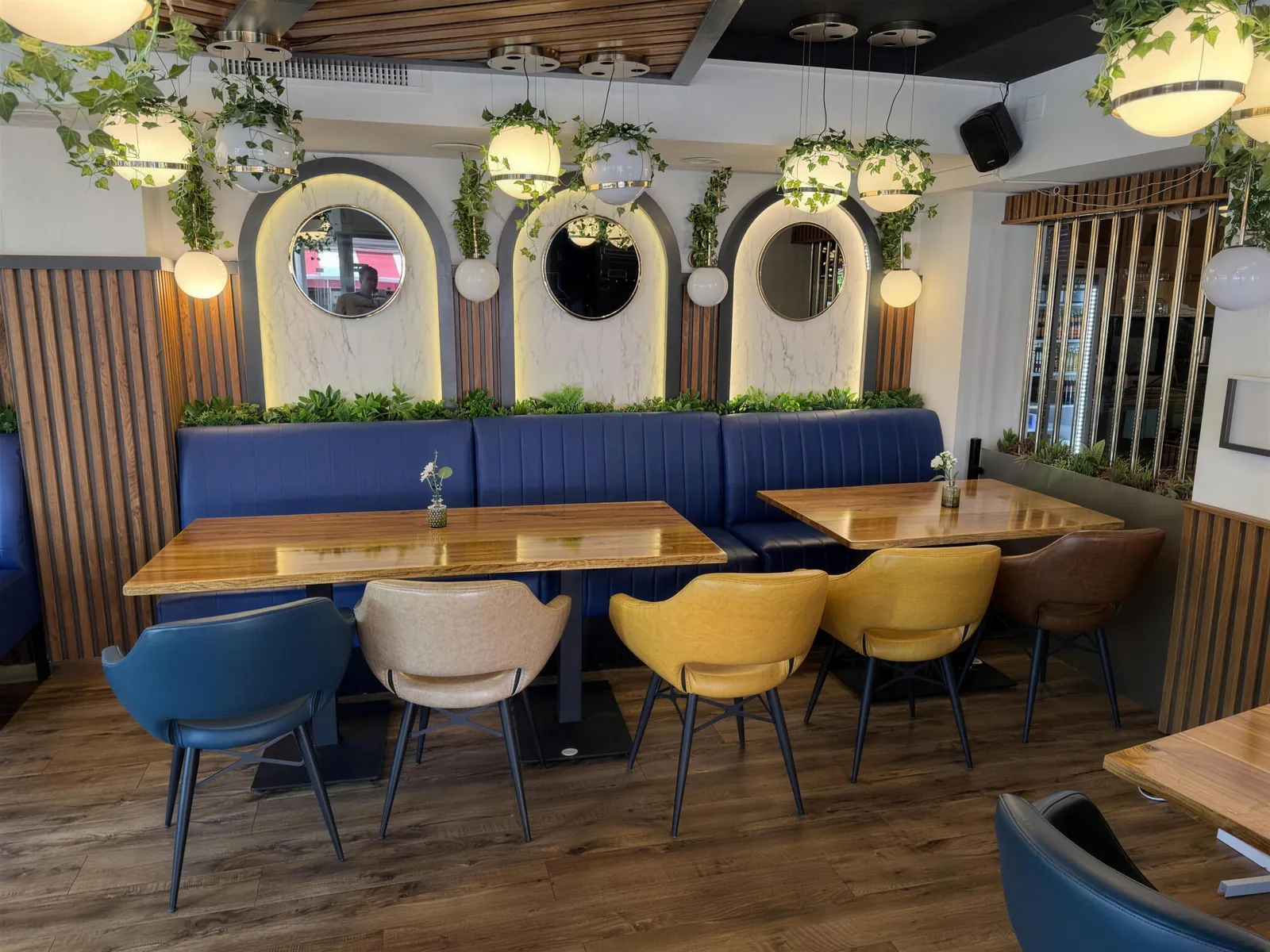 Gemütliche Booth-Sitzecke mit blauen Polstern, Bogenspiegel und hängenden Pflanzen im King Kebap Lünen
